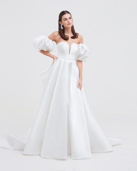In questa foto una modella indossa un abito da sposa in mikado di seta bianco, con scollo a cuore e piccola scollatura a V centrale. Le maniche sono balloon e rimovibli