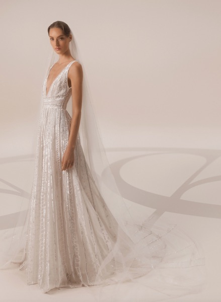 In questa foto una modella indossa un abito da sposa con applicazione all over di luminose perline e cristalli