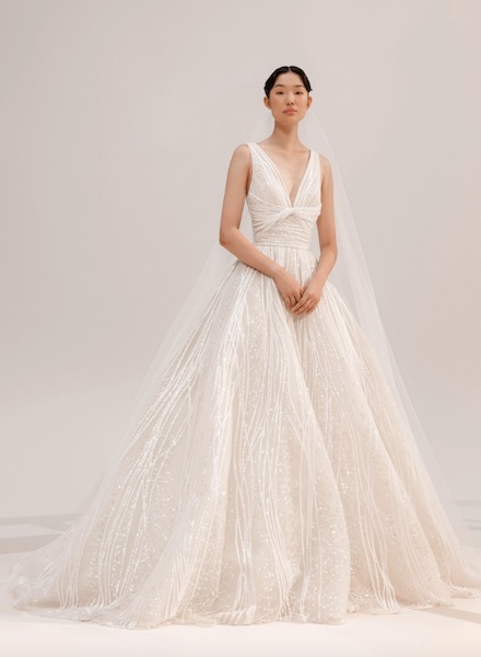 In questa foto una modella indossa un abito da sposa ricamato con fili di perle verticali