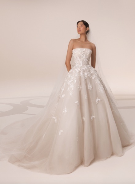 In questa foto una modella indossa un vaporoso abito da sposa con gonna in tulle e applicazioni di fiori 3D 