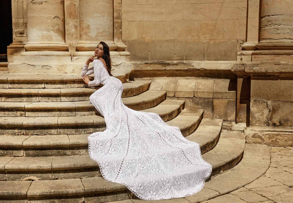 In questa immagine un abito da sposa Claudio Di Mari 2023 interamente ricamato in pizzo con una maxi coda.