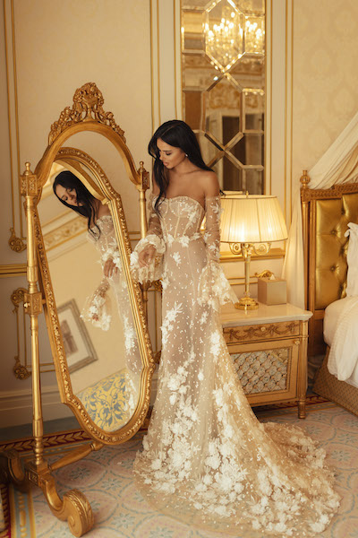 In questa foto una modella indossa un abito da sposa sirena color nude, con fiori 3D bianchi applicati all over