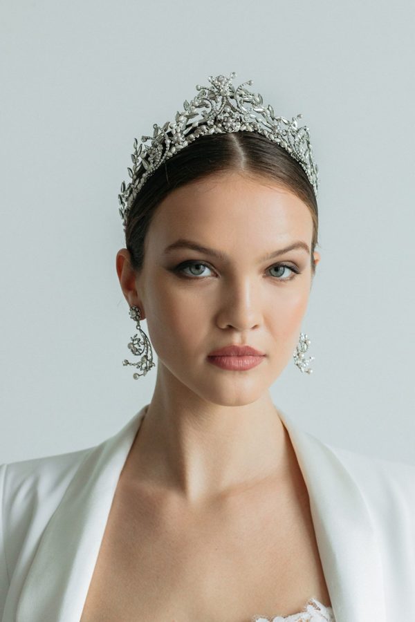 In questa foto una modella indossa una tiara da sposa in argento e cristalli con orecchini abbinati di Maria Elena Headpieces
