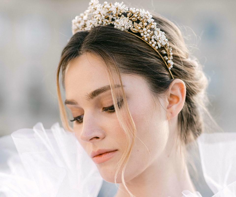 In questa foto una modella mostra una delle acconciature sposa 2023 raccolta e decorata da una tiara di perline