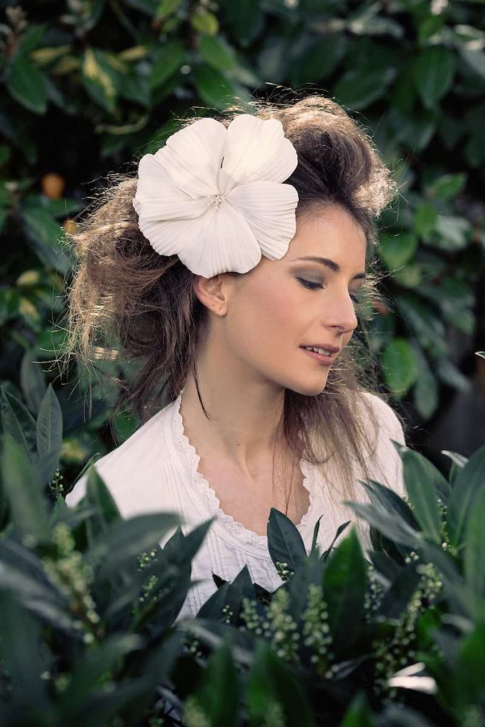 In questa foto una modella indossa un fermaglio con maxi fiori di stoffa di colore bianco