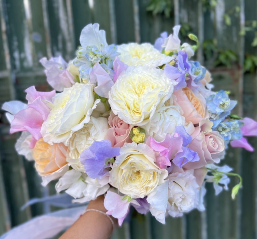 In questa foto un bouquet sposa 2023 con fiori viola, gialli e rosa.