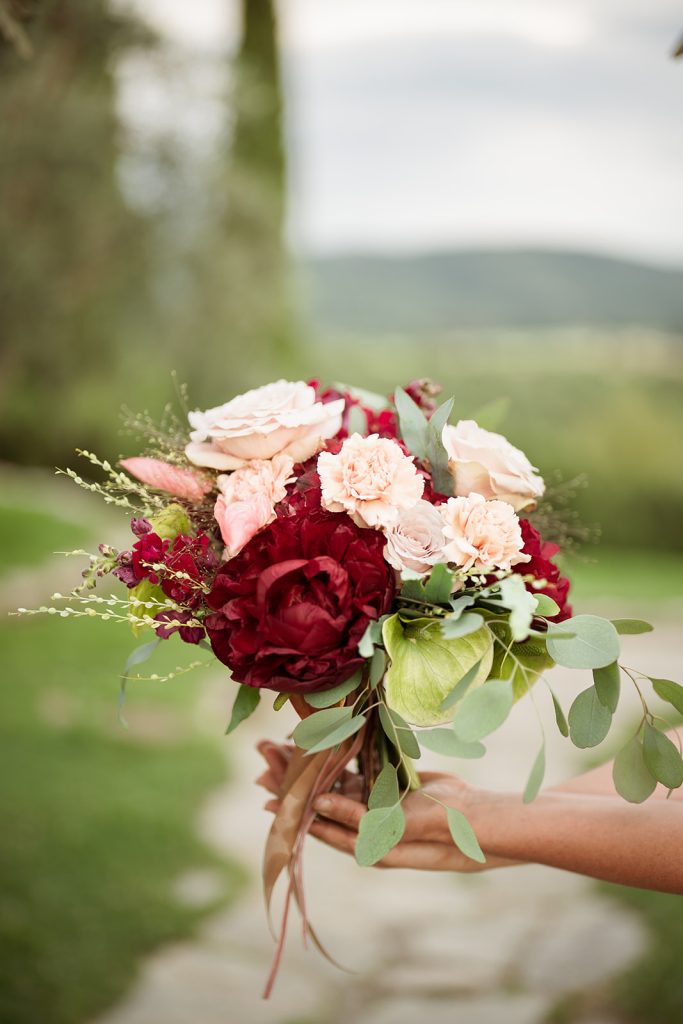 In questa foto un mazzo di fiori per la sposa con rose rosa e peonie rosse.