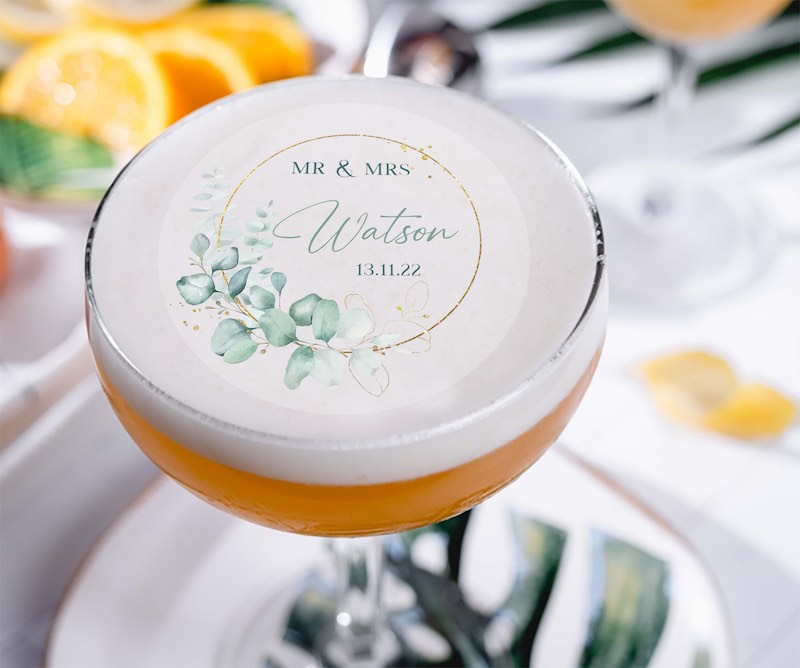 In questa foto un cocktail inquadrato dall'alto e poggiato su un piattino. Sulla superficie del cocktail è posizionato un cocktail topper, una delle idee matrimonio 2023