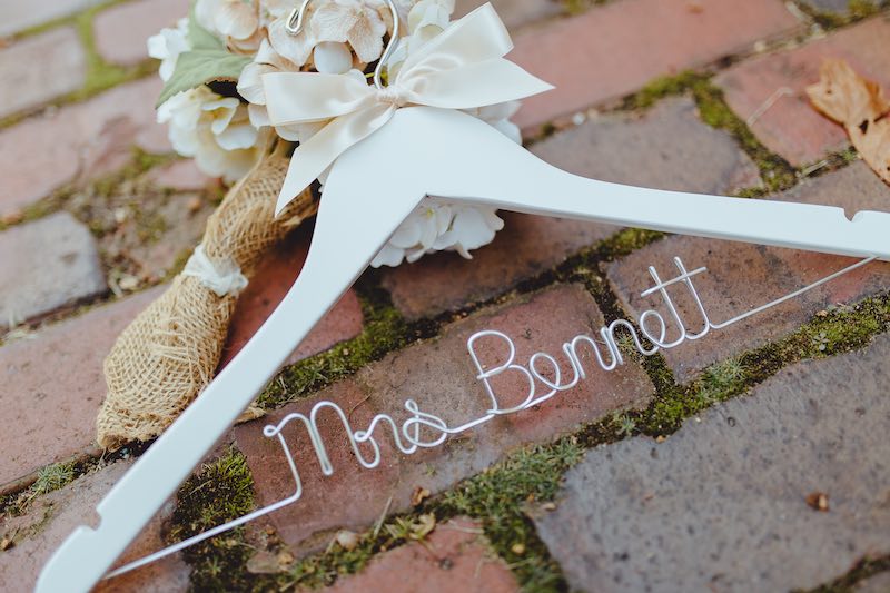 In questa foto una gruccia personalizzata da sposa di colore rosa decorata con fiocco rosa e la scritta "Mrs Bennett"