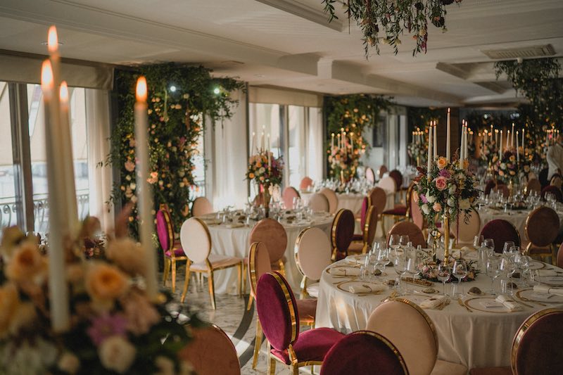In questa foto una sala per matrimonio allestita con fiori sui pilastri e sul tetto e sedie di velluto di colore bordeaux e rosa cipria
