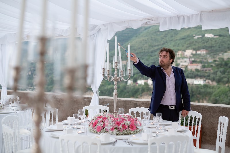 In questa foto il wedding planner Stefano Miranda accende le candele di un candelabro posto al centro di un tavolo per matrimonio
