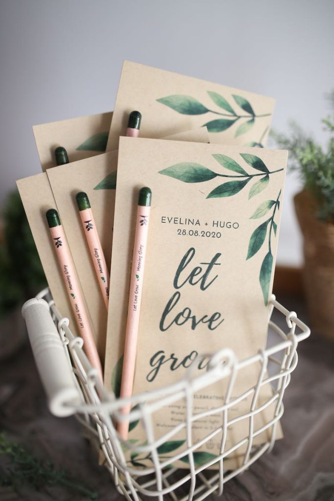 In questa foto save the date per matrimonio ecosostenibile composti da una matita piantabile e carta riciclata decorata con foglie verdi