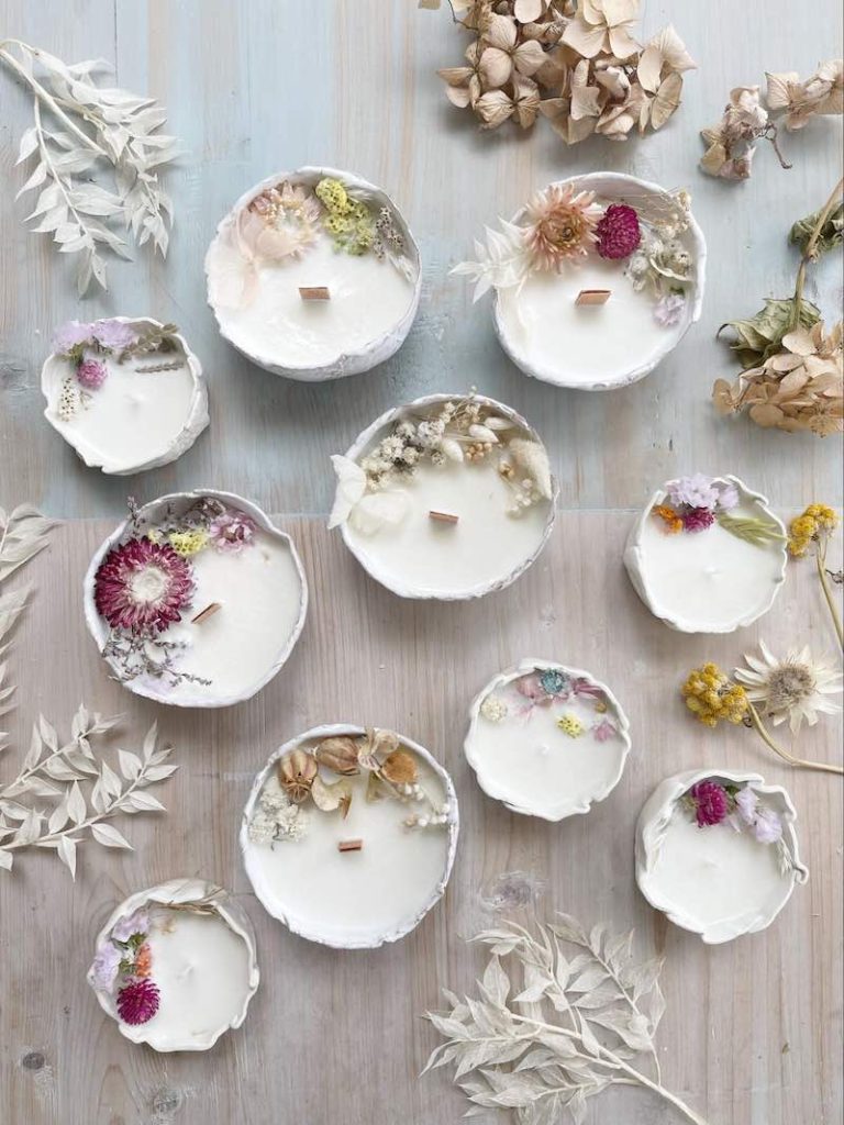 In questa foto inquadrata dall'alto candele bianche artigianali decorate con fiori stabilizzati 