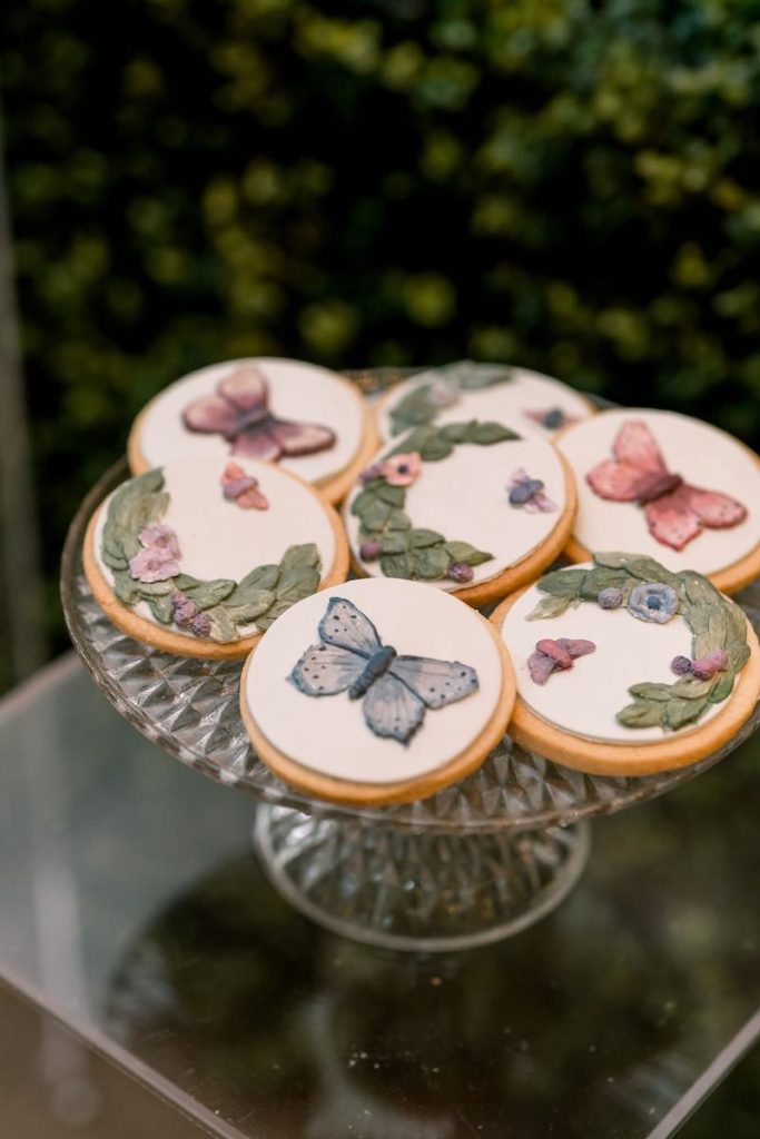 In questa foto biscottini decorati con farfalle di colore azzurro e rosa e foglie 3D