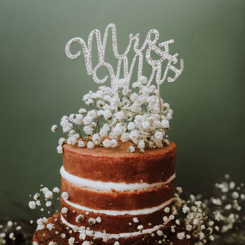 In questa foto una naked cake decorata con gypsophila bianca e la scritta bianca Mr&Mrs