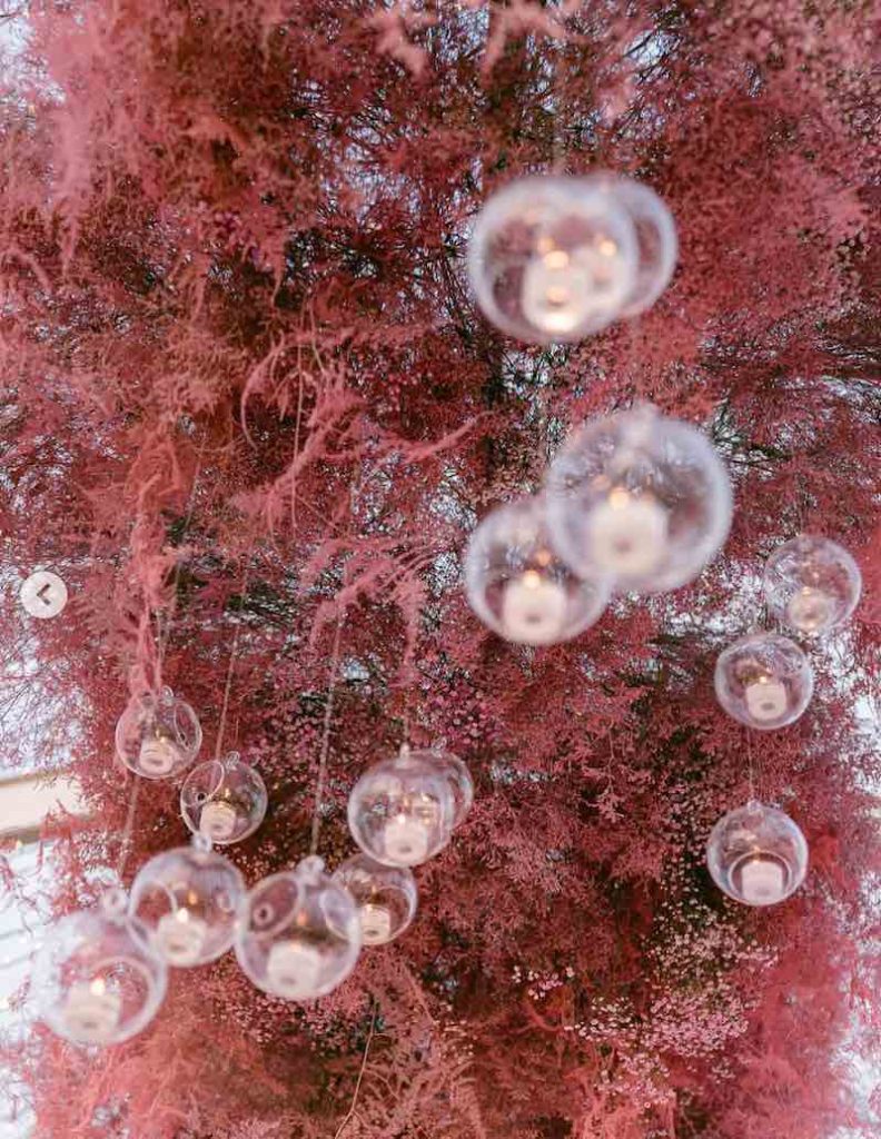 In questa foto il dettaglio di una composizione area composta da gypsophila colore magenta e candele di vetro pendenti con candeline bianche