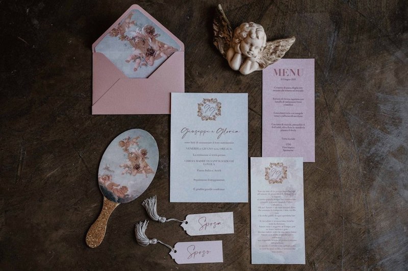 In questa foto una wedding stationery in stile Bridgerton nei toni dell'oro e del rosa