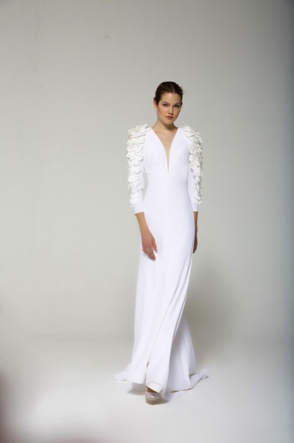 In questa foto una modella indossa un abito da sposa in crêpe modello a sirena con scollatura a V e maniche lunghe con fiori 3D 