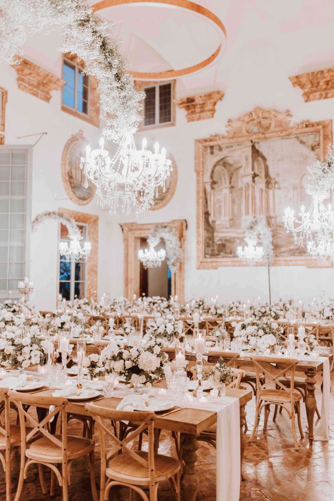 In questa immagine un allestimento floreale matrimonio 2023 con elementi sospesi e centrotavola con delicati fiori bianchi. 