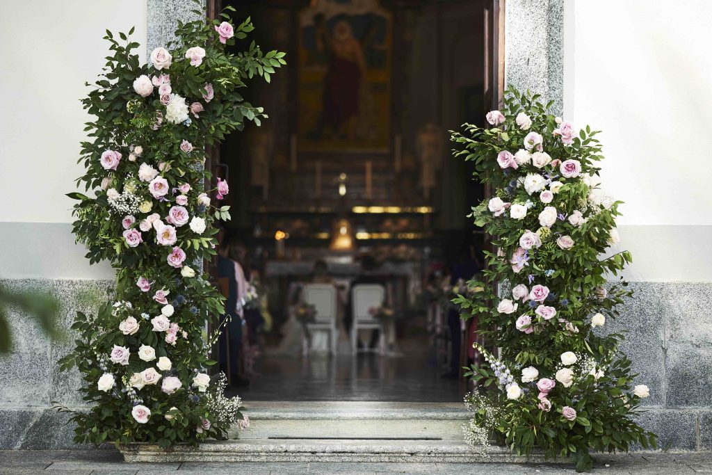 In questa immagine un allestimento floreale matrimonio 2023 di una chiesa con un imponente struttura di realizzata con rose rosa. 