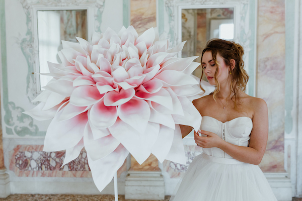 In questa foto una modella tiene tra le mani un fiore di carta gigante di Incartesi, si tratta di una delle idee per le nozze più originale in fatto di allestimenti matrimonio