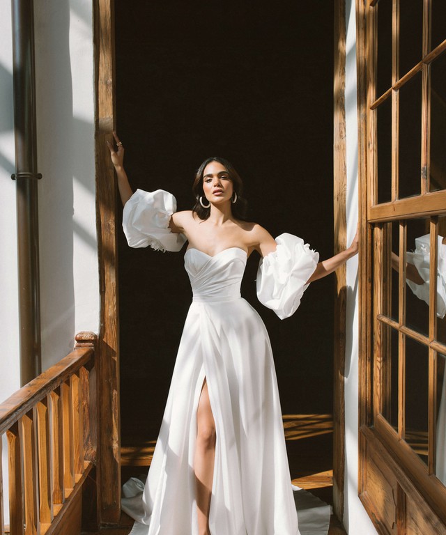 In questa immagine un abito da sposa con spacco e maniche voluminose della collezione White Garden di Blammo-Biamo