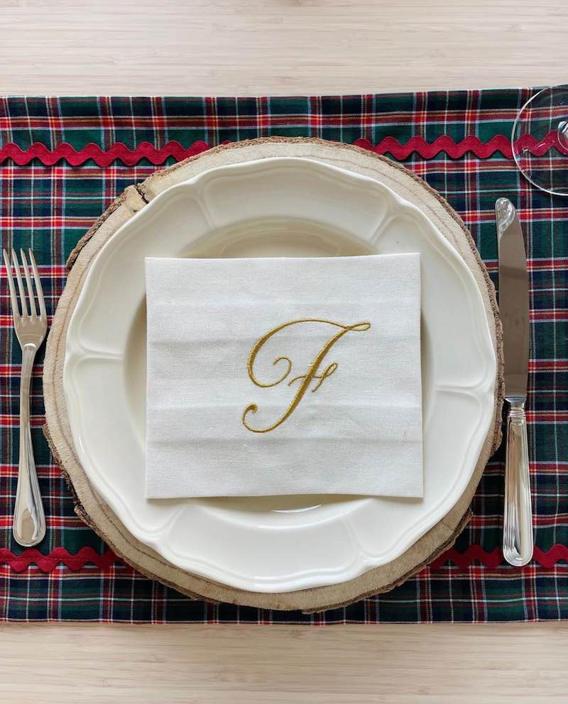 In questa foto un'idea di bomboniere matrimonio 2023: un tovagliolo ricamato con l'iniziale dell'ospite "F" di colore oro posizionato su un piatto di porcellana