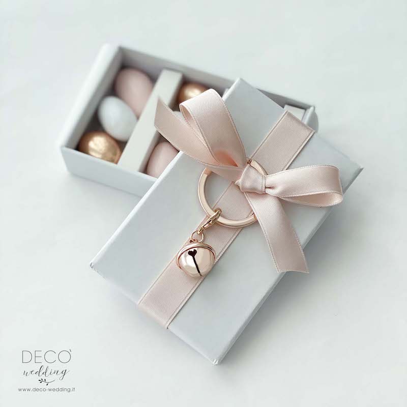 In questa foto una scatolina per confetti di colore rosa con portachiavi chiamangeli rose gold