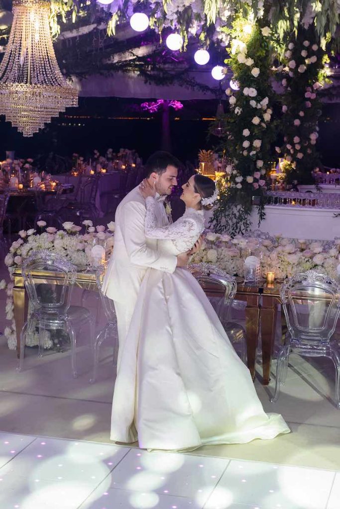 In questa foto due sposi durante il loro primo ballo nella location delle loro nozze decorate con rose, ortensie e gypsophila di colore bianche, tavoli colore oro e lampadari di cristallo