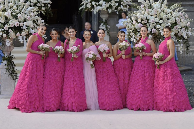 In questa foto le 8 damigelle della sposa in abiti color magenta posano davanti all'ingresso della chiesa di Cetara. Gli abiti presentano scollature diverse e gonne con ruches all over