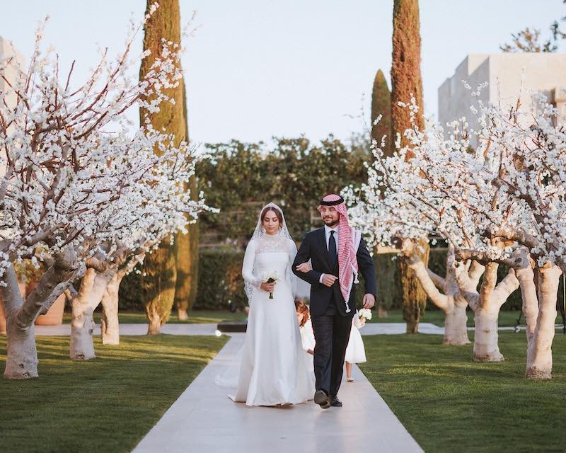 In questa foto la principessa Iman di Giordania cammina tra alberi di ciliegio al braccio del fratello maggiore Hussein
