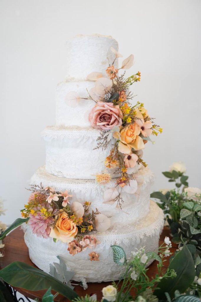 In questa foto una delle torte matrimonio 2023 a 5 piani decorata con glassa bianca e fiori 