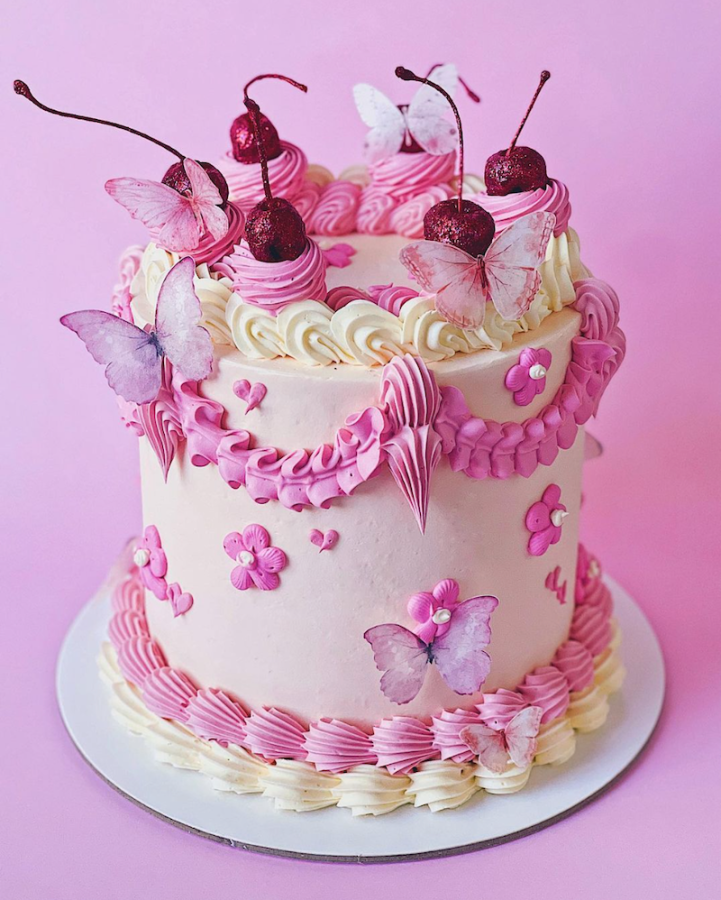 In questa foto una torta Lambeth Cake decorata con glassa di colore rosa e bianco, farfalle di zucchero e ciliegie glassate con glitter