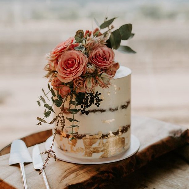 In questa foto una naked cake decorata a foglia oro e con rose di colore rosa