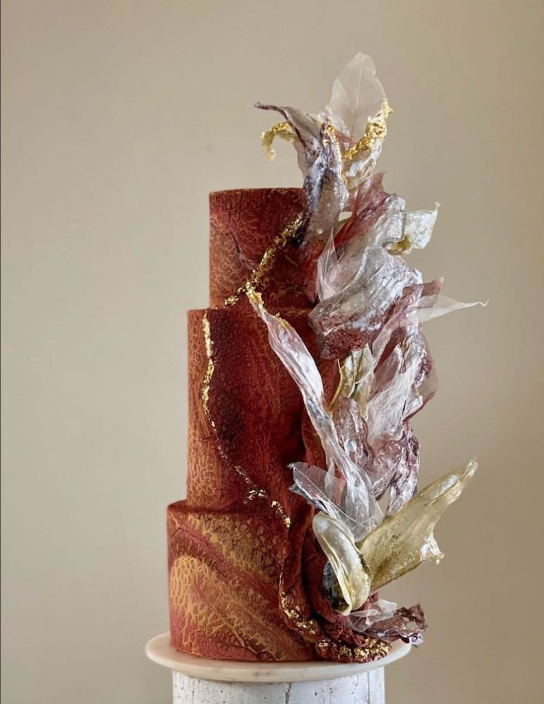 In questa foto una torn paper cake decorata nei toni del bordeaux e dell'oro 