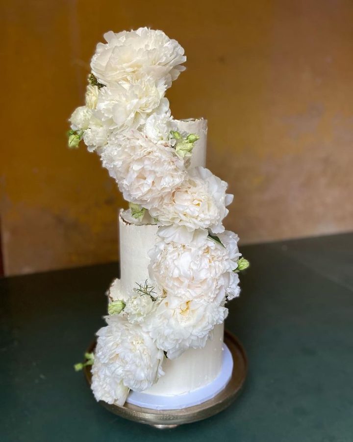 In questa foto una delle torte matrimonio 2023 a 3 piani decorata con glassa di colore bianco e una spirale di peonie di colore bianco