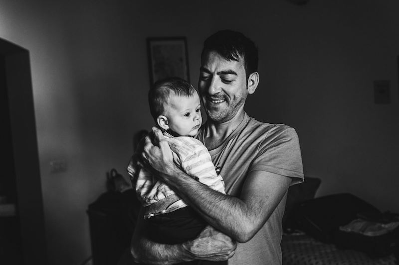 In questa foto in bianco e nero di Vincenzo Aluia lo sposo con in braccio il suo bambino durante la preparazione per il matrimonio