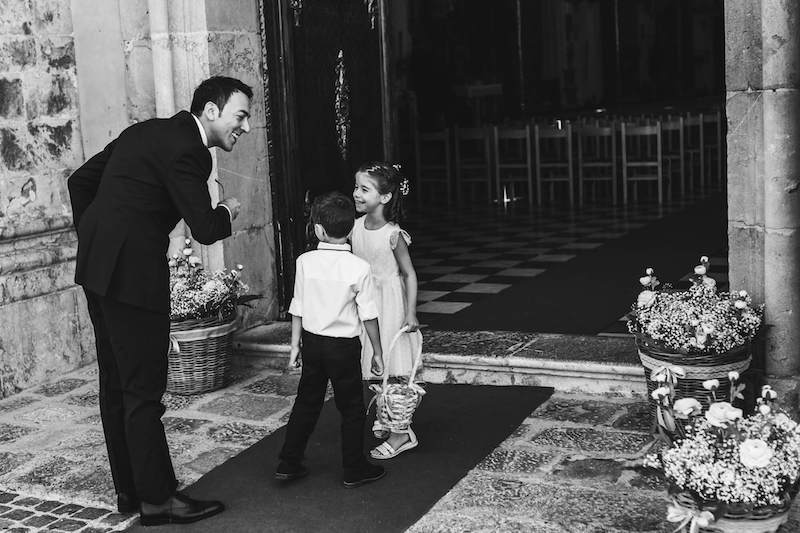 In questa foto in bianco e nero di Vincenzo Aluia lo sposo scherza con il paggetto e la damigella davanti all'ingresso della chiesa del matrimonio