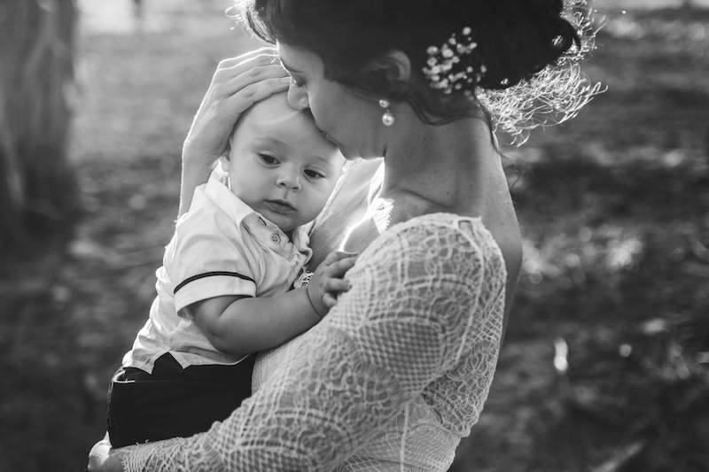 In questa foto in bianco e nero di Vincenzo Aluia una sposa tiene in braccio e bacia sulla fronte il suo bambino