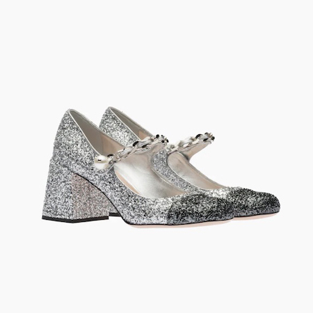 In questa foto un paio di Mary Jane glitterate: sono color silver all over e solo in punta nere. Il modello, di Miu Miu, fa parte delle proposte più trendy in fatto di scarpe da cerimonia donna 2023