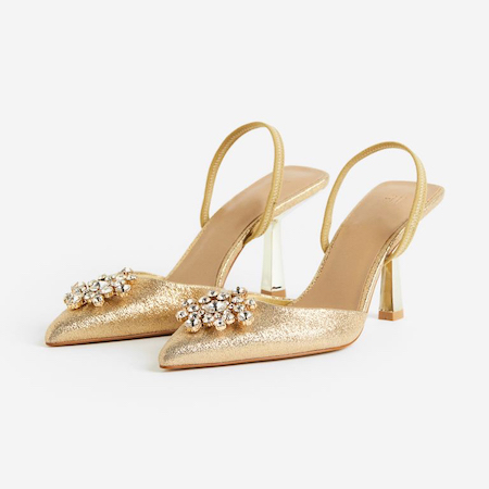 In questa foto un paio di slingback gold, con maxi broche in punta. Le scarpe, perfette per le invitate ad un matrimonio, sono di H&M