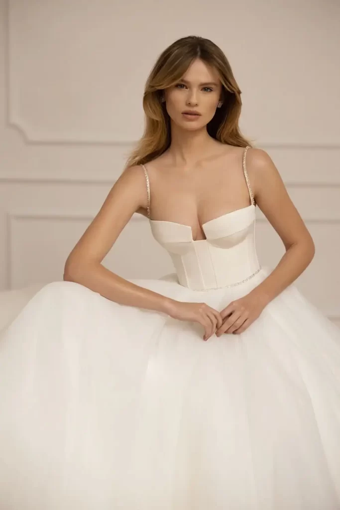 In questa foto una modella indossa un abito da sposa Eva Lendel 2023 con gonna in tulle e bustier in crêpe con scollo squadrato con bretelle sottili gioiello