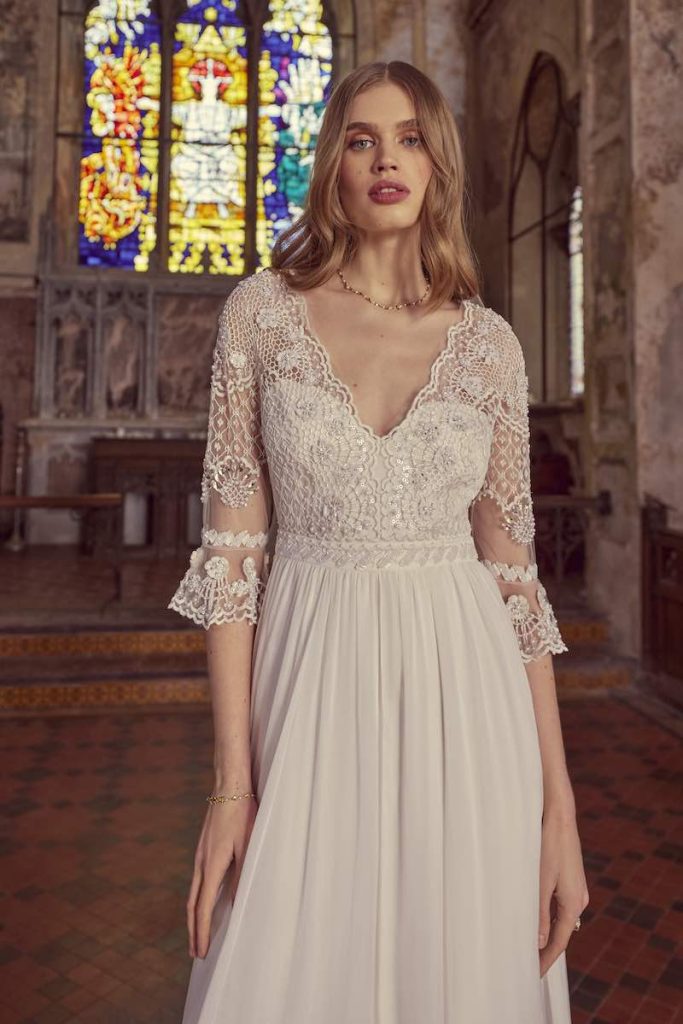 In questa foto una modella indossa un abito da sposa Temperley Bridal 2024 con corpetto ricamato, scollo a V, maniche a tre quarti a corolla