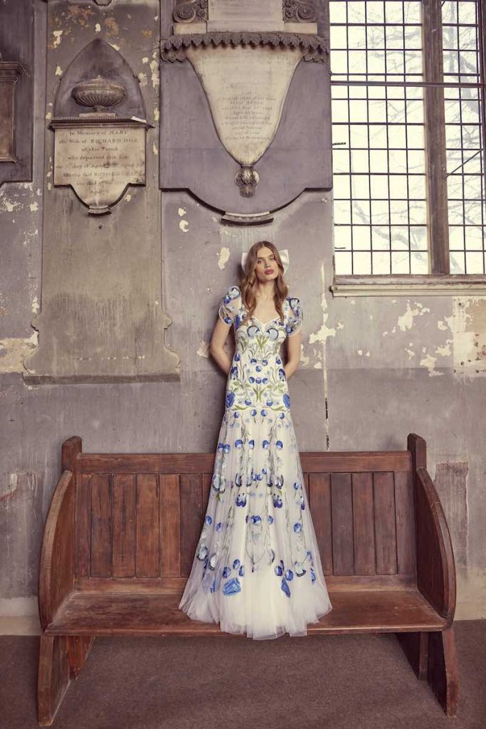 In questa foto una modella indossa un abito da sposa Temperley Bridal 2024  in tulle con decori floreali di colore blu fiordaliso
