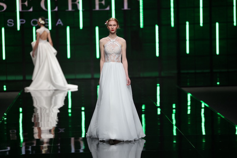 In questa foto una modella sfila indossando un abito da sposa Mysecret Sposa 2024 modello scivolato con gonna in chiffon e corpetto in pizzo ricamato 