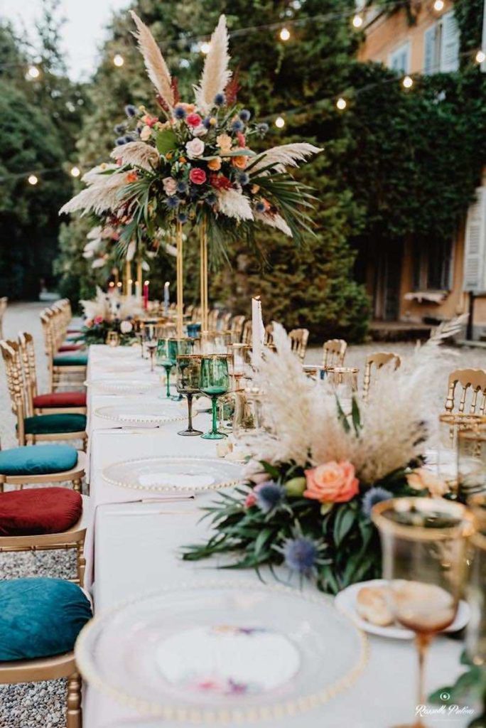In questa foto uno degli allestimenti matrimoni di Idee da Sogno: una tavola decorata con composizioni e altate di pampas e fiori di colore e rosso e rosa