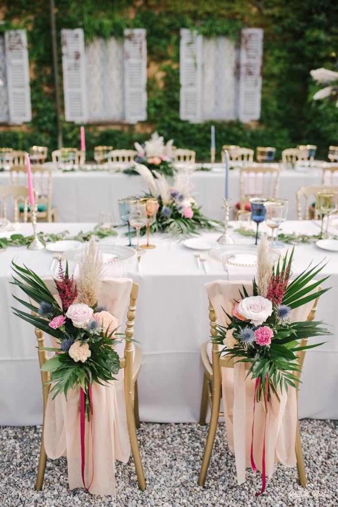 In questa foto il dettaglio della decorazione delle sedie degli sposi realizzata da Idee da Sogno con palme e rose di colore bianco e rosa