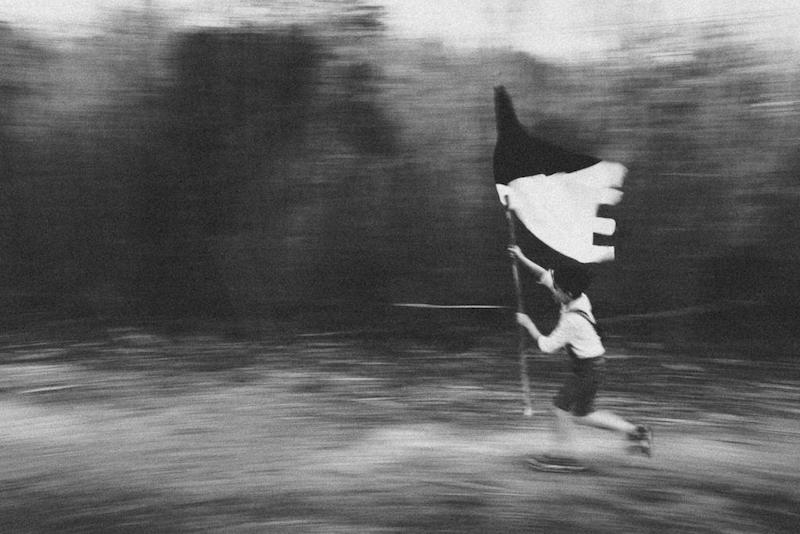 In questa foto in bianco e nero di Fabio Magara un bambino che corre con una bandiera in mano