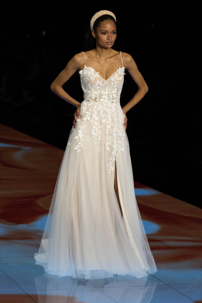 In questa immagine un abito da sposa Modeca 2024 con corpetto con fiori in 3D che scendono giù lungo la gonna.