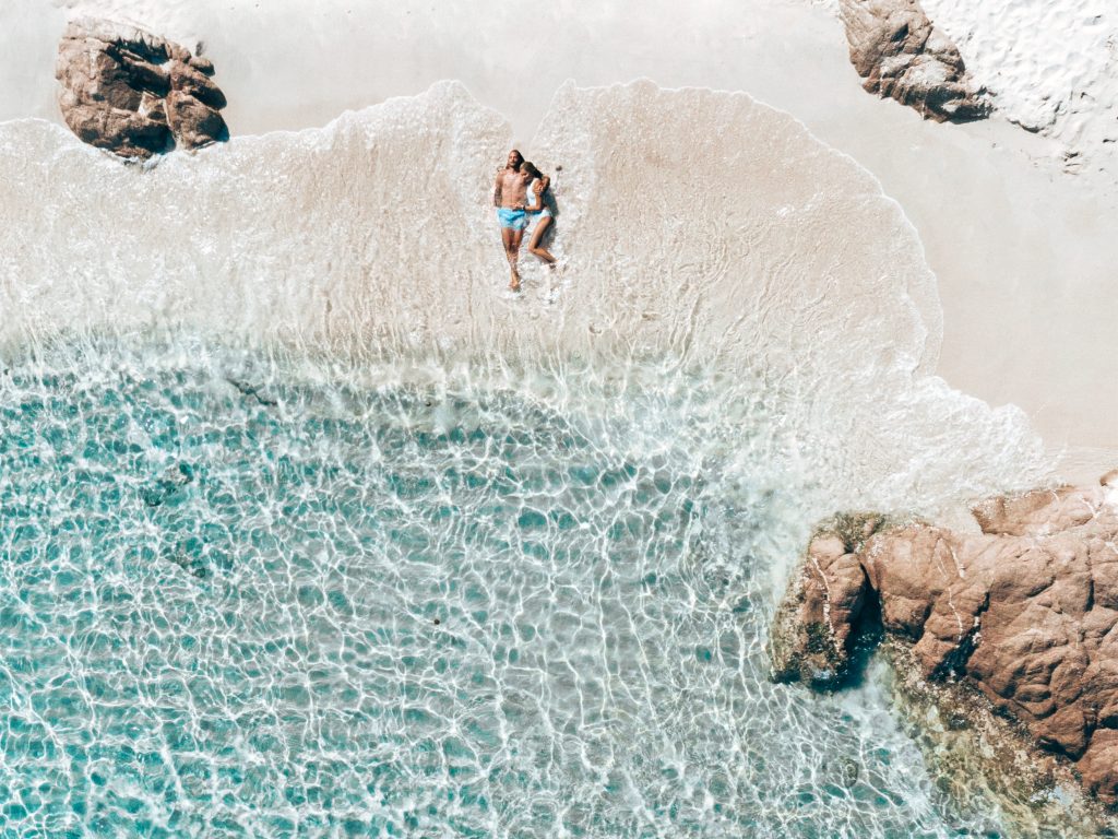 In questa immagine una coppia felice nel mare della Sardegna per  festeggiare con un viaggio l'anniversario di matrimonio